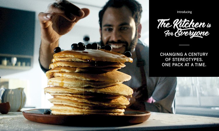 Man standing in kitchen with a stack of pancakes