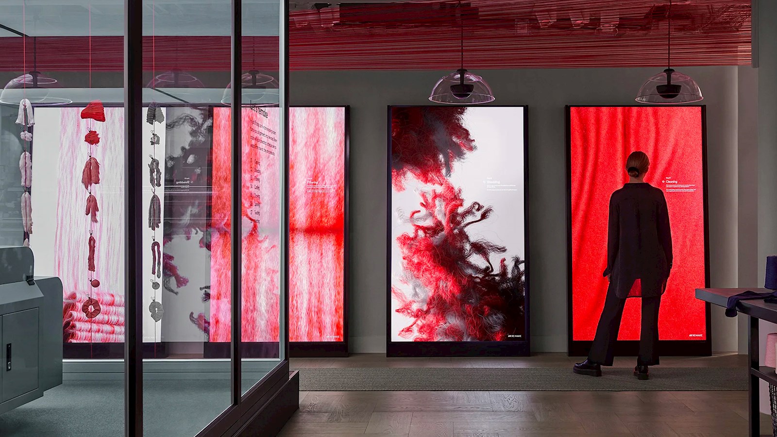 Woman standing in front of floor to ceiling screen showing looped red thread. Part of AKQA and Universal's campaign for H&M, Looop