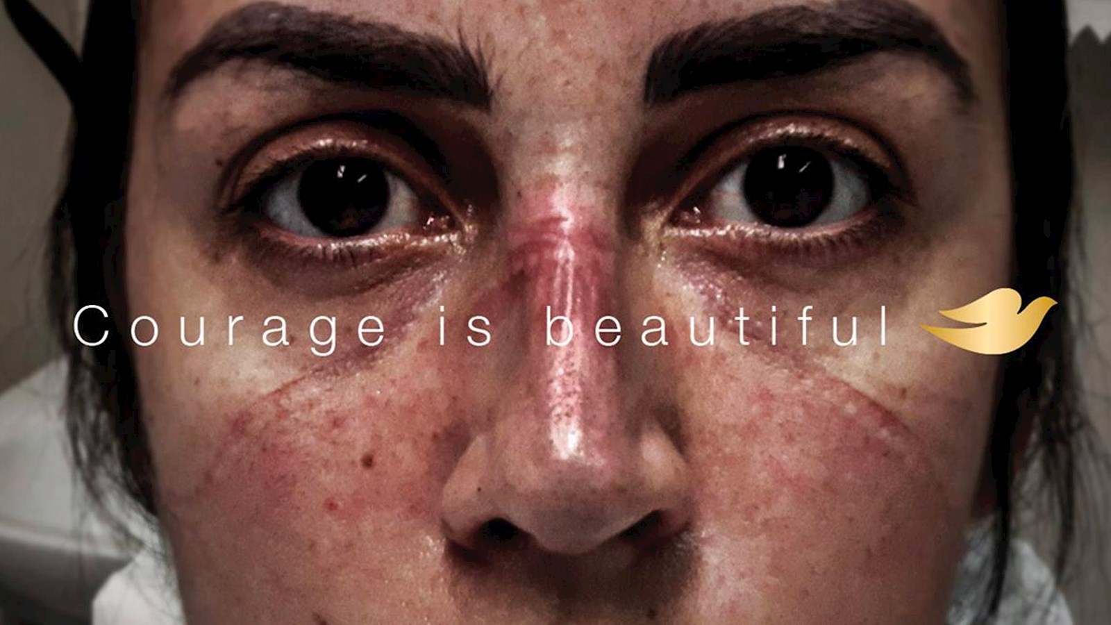 Close up of a health worker's face with "Courage is Beautiful" overlaid with the Dove logo
