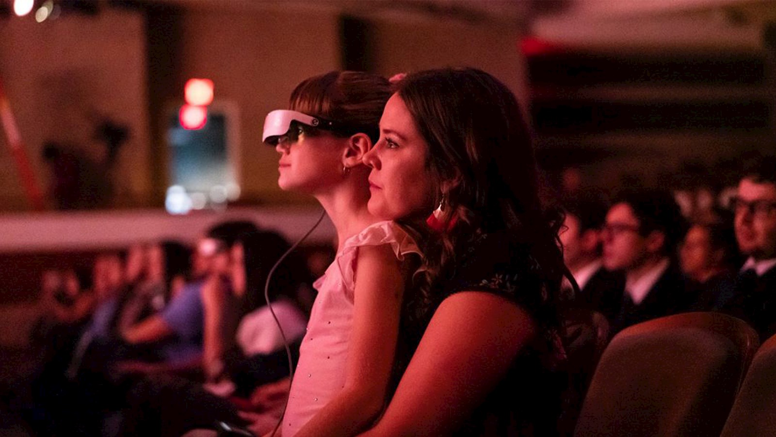 Girl sat on her Mother's knee watching the ballet with Dell's eSight glasses on