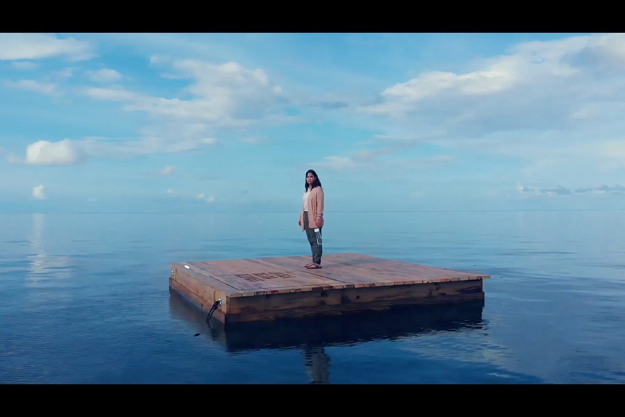 Woman stood on wooden island in the ocean