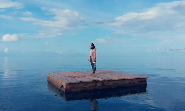 Woman stood on wooden island in the ocean