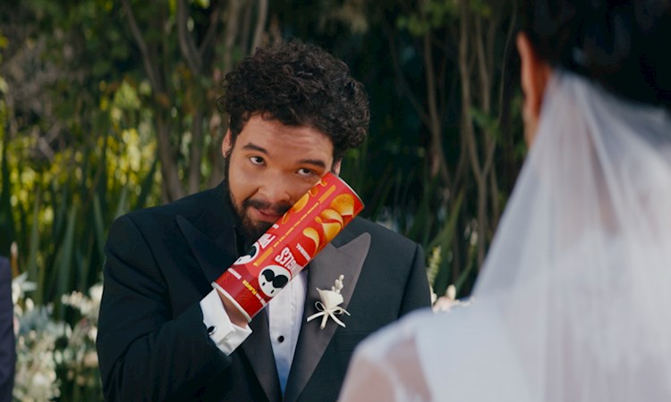 Man in a wedding suit, getting married, with a Pringles tube stuck on his hand