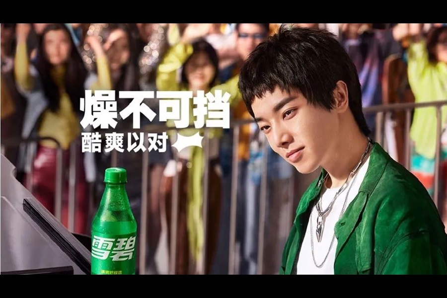 Hua Chenyu looking at a Sprite bottle on stage in front of a crowd