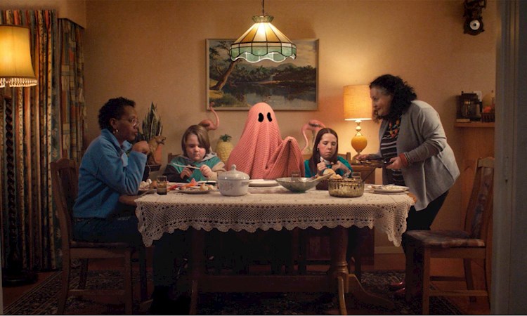 People eating dinner round a table, with one of them dressed as a ghost