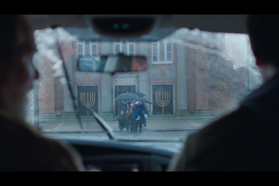 View looking through a car windscreen as a group of people coming out of a synagogue