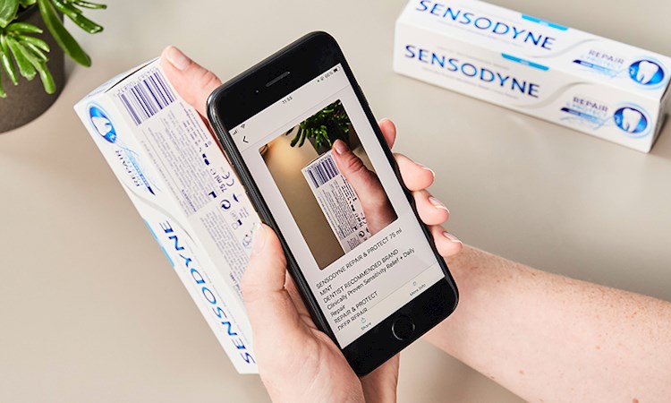 Someone with a phone scanning a barcode on a toothpaste packet to read the label with Seeing AI