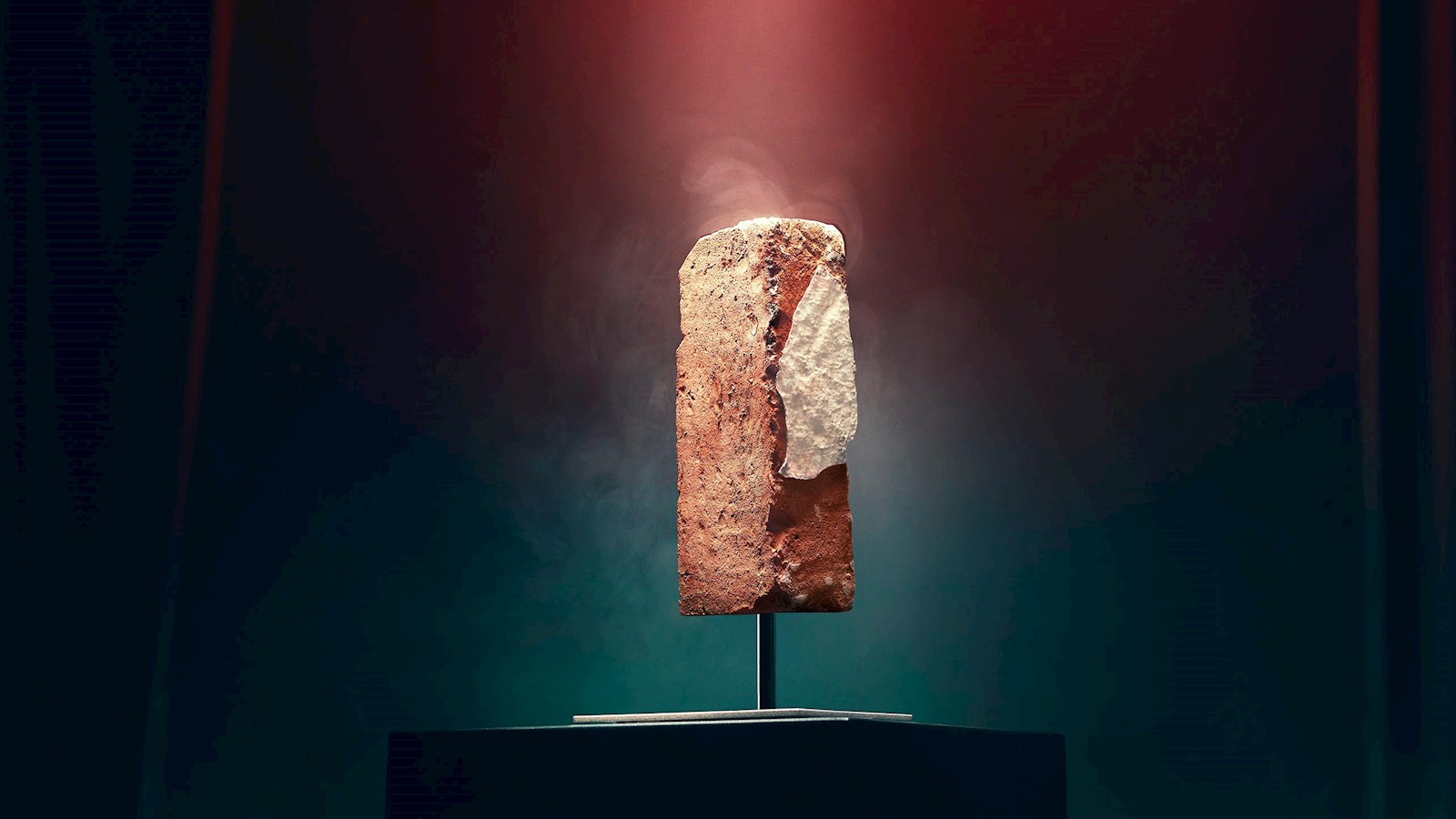 A brick from the La Rocca nightclub on a pedestal downlit in a beautiful glow on a dark backgrounf