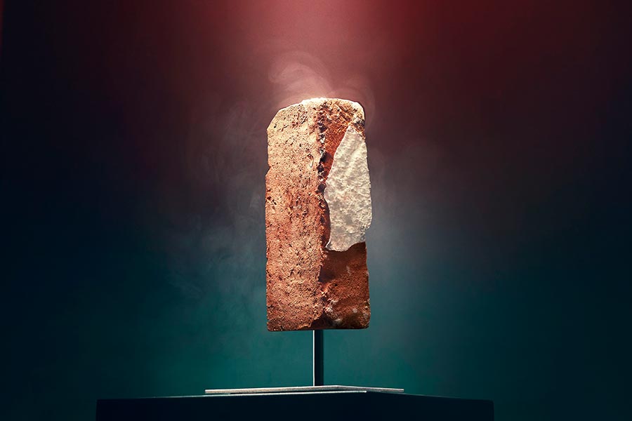 A brick from the La Rocca nightclub on a pedestal downlit in a beautiful glow on a dark background