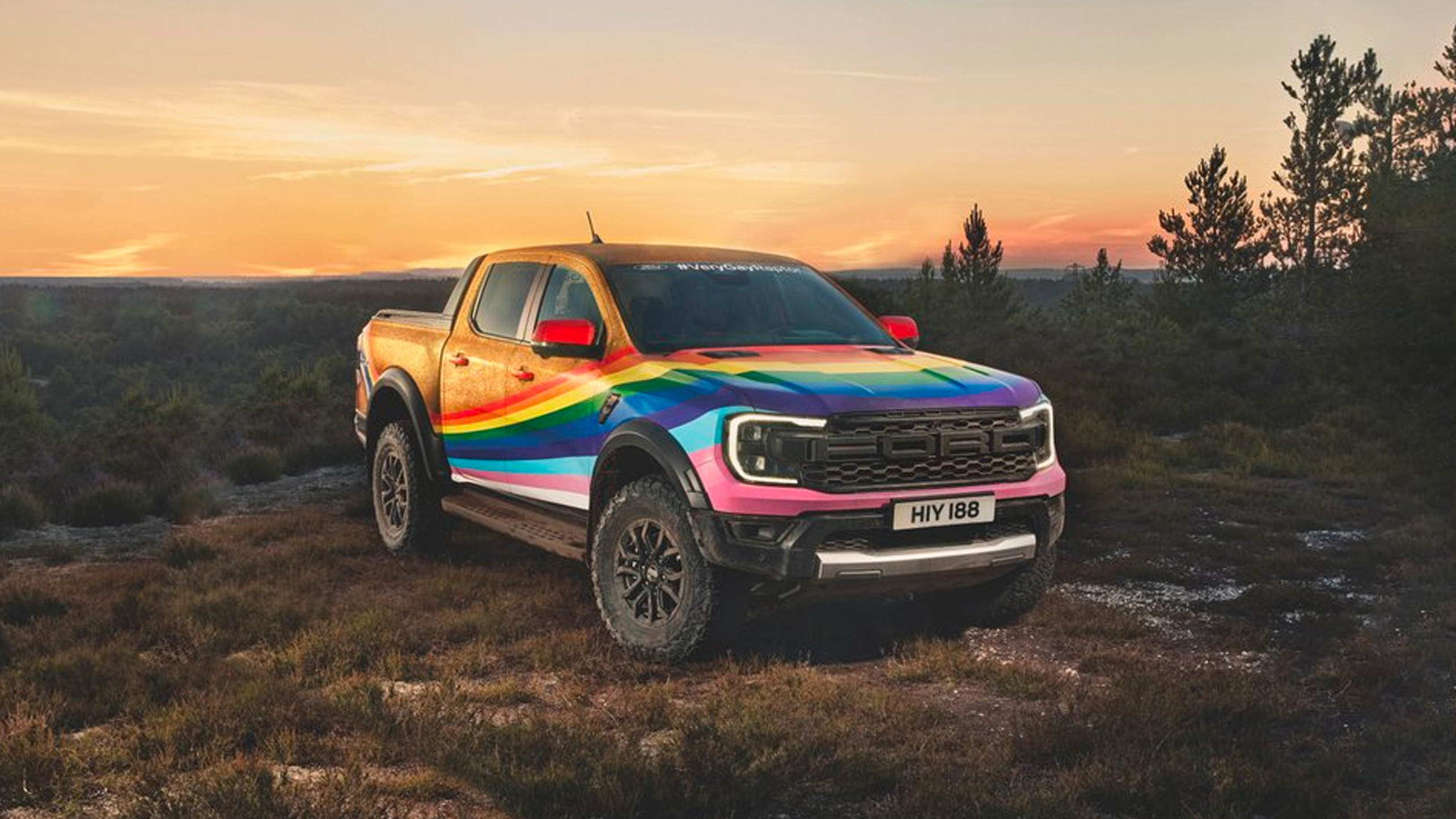 Ford truck painted with a rainbow in the middle of a mountain landscape