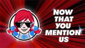 Wendy's logo with sunglasses and 'Now that you mention us' text