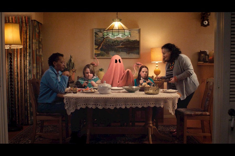 People sitting round a dining table with a ghost in the middle