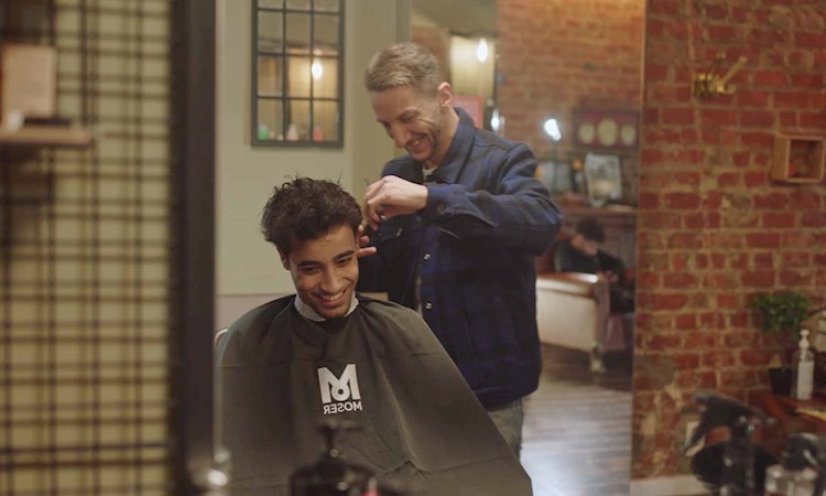 Young smiling man getting his hair cut by a hairdresser in a cool barber salon in Brussels