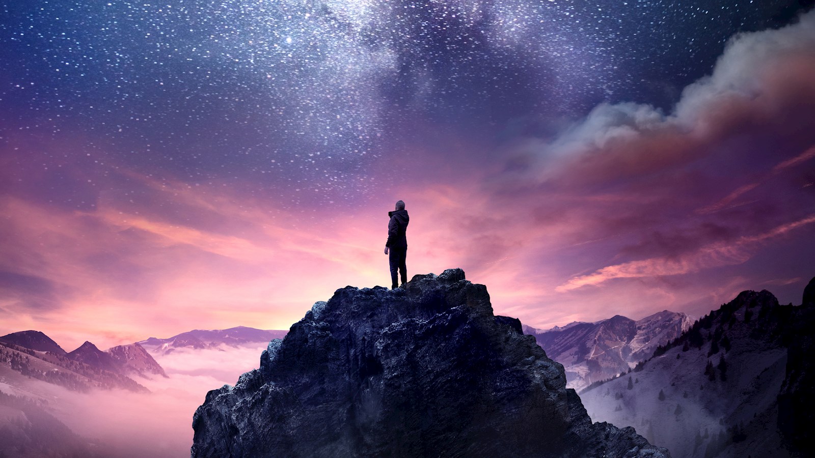 Person on top of a mountain looking up at the stars 