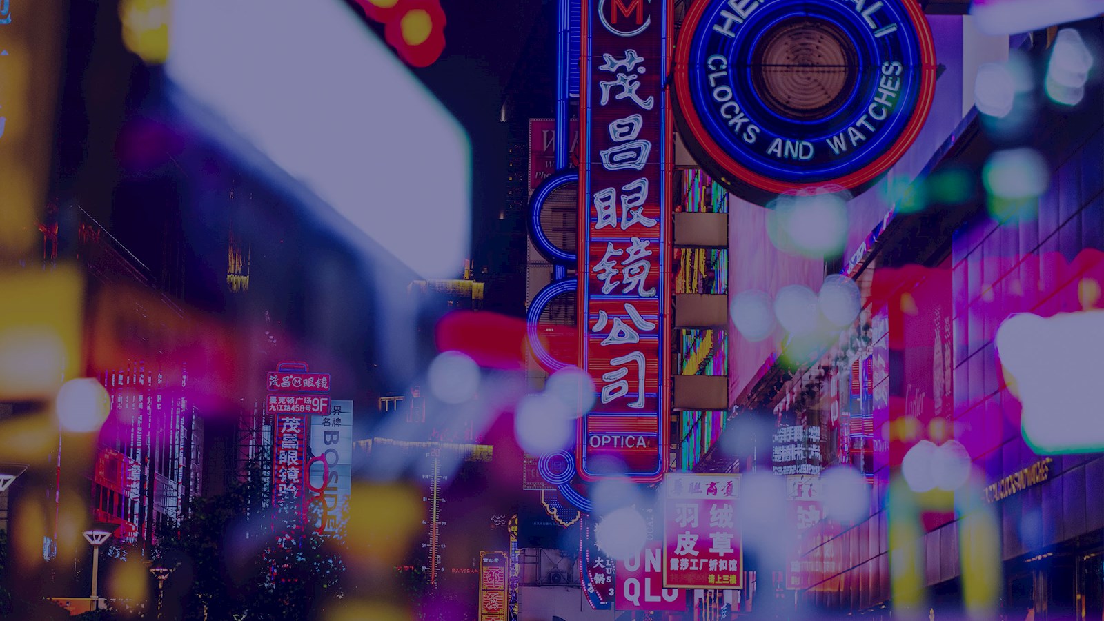 Photograph of a street in China with lots of bright lights and shop signs