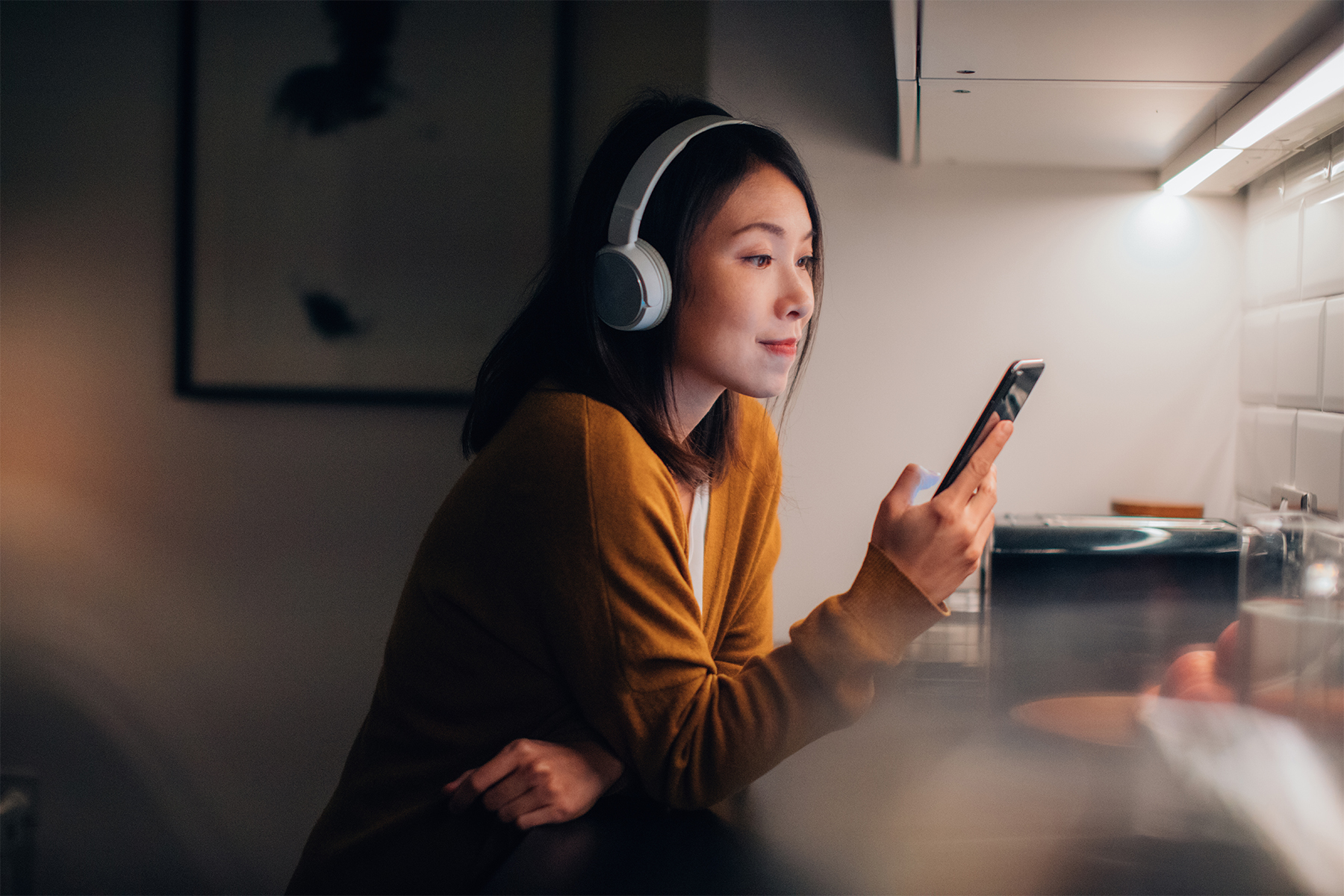 Young Woman With Bluetooth Headphones Listening To Music On Smartphone