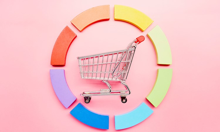 Pie chart made of colourful building blocks and a small shopping cart on pink background