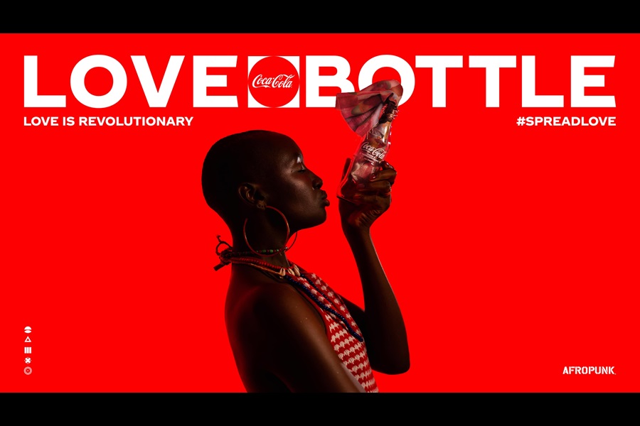 Profile view of a person holding Coca-Cola bottle with the words "Love Bottle, Love is Revolutionary" #Spreadlove on as a headline